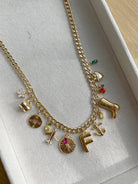 Gold necklace with various charms on a white surface