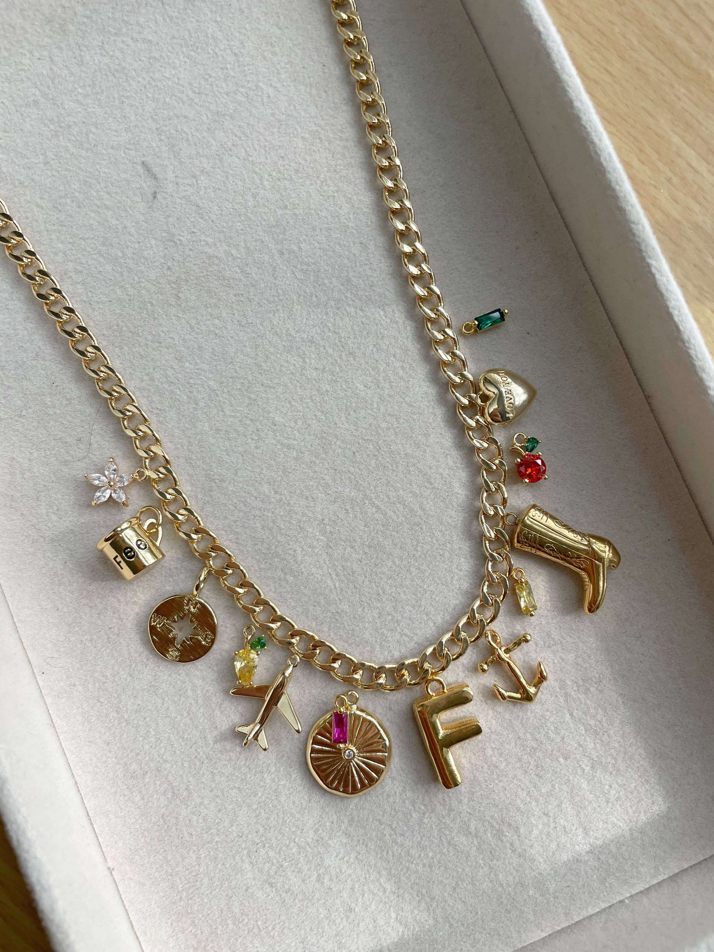 Gold necklace with various charms on a white surface