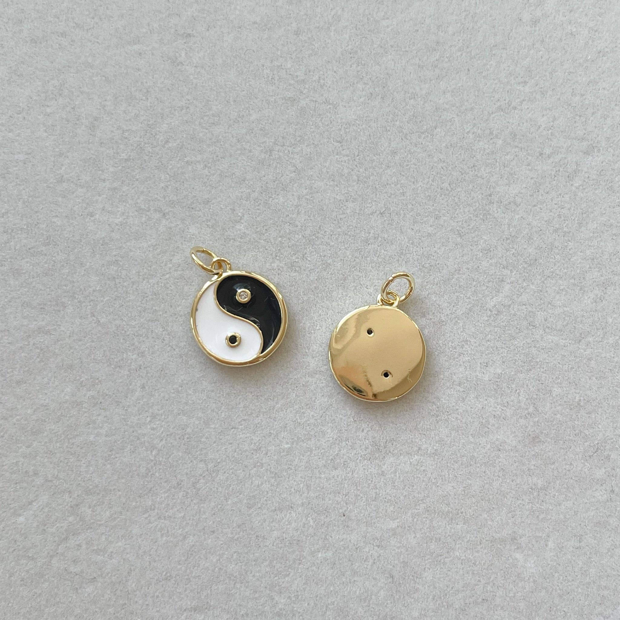 Two gold pendants on a gray background
