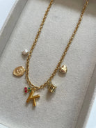 Gold necklace with various charms on a light gray background
