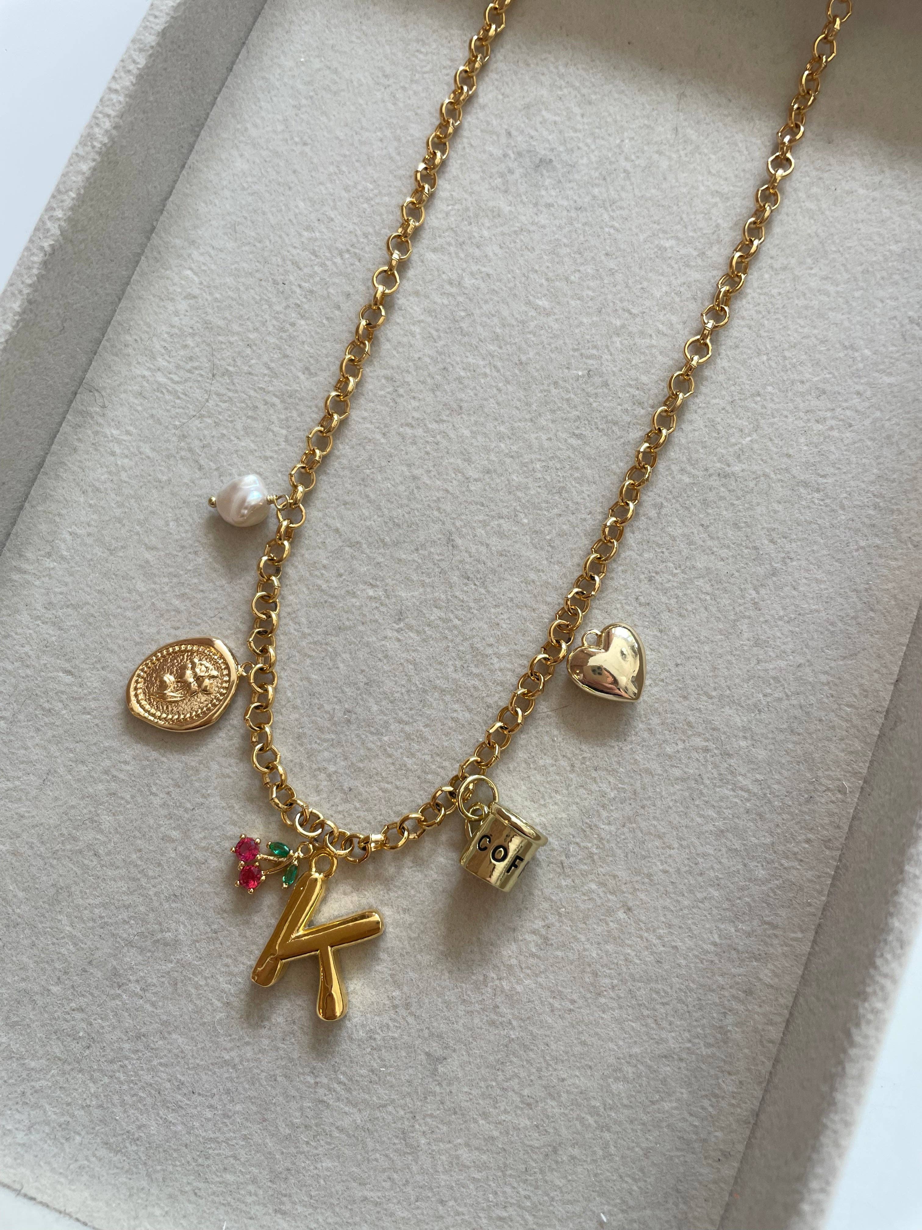 Gold necklace with various charms on a light gray background