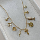 Gold necklace with various charms on a light gray surface