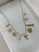 Gold necklace with various charms on a light gray background