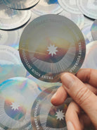 Holographic disc with motivational text held by a hand against a background of similar discs.