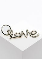 Silver 'love' charm on a white card with a gray border