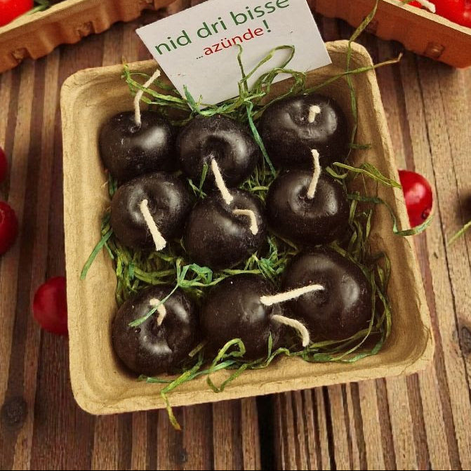 Cardboard baskets filled with red and black 'cherries' on a wooden surface.